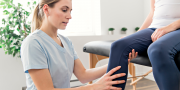 Vrouwelijke fysiotherapeute behandelt een man aan zijn been