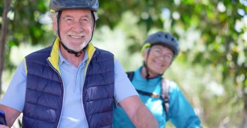 Senioren man en vrouw op de fiets met een fietshelm op